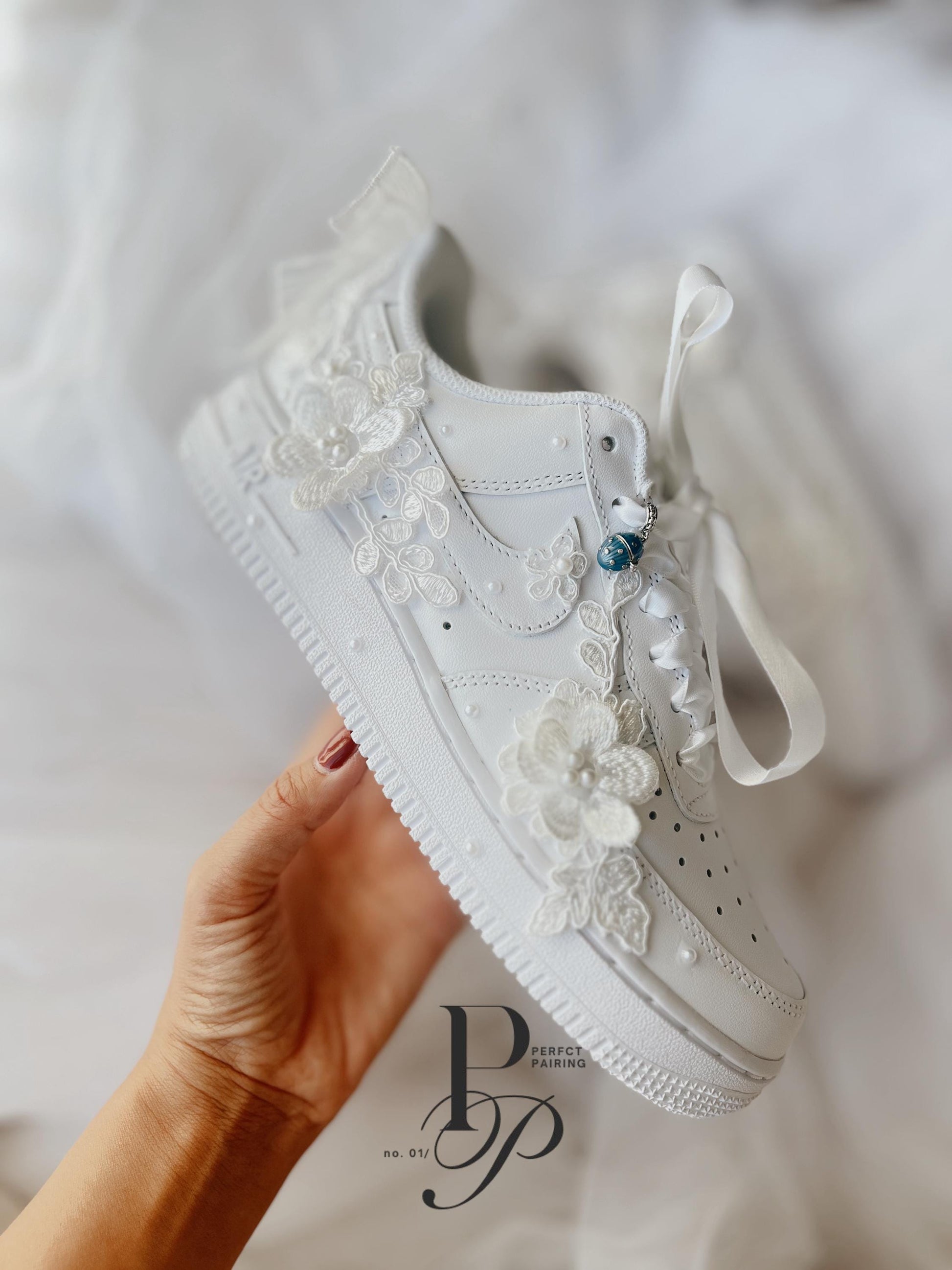 Hand embroidered Nike Air Force wedding sneakers featuring floral embroidery and pearl accents, designed as custom bridal shoes for brides.